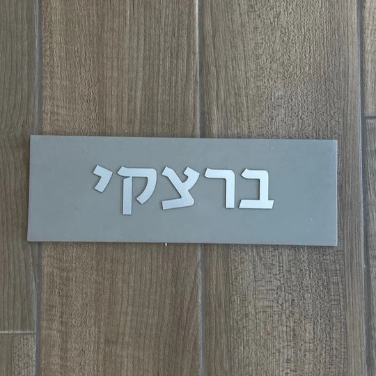 A design sign for a door made of clean concrete in gray with silver lettering - Israel series